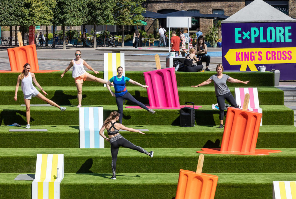 Frame 80's Aerobics class in the the Lollipop Lounge on the grass steps of Granary Sq at King's Cross