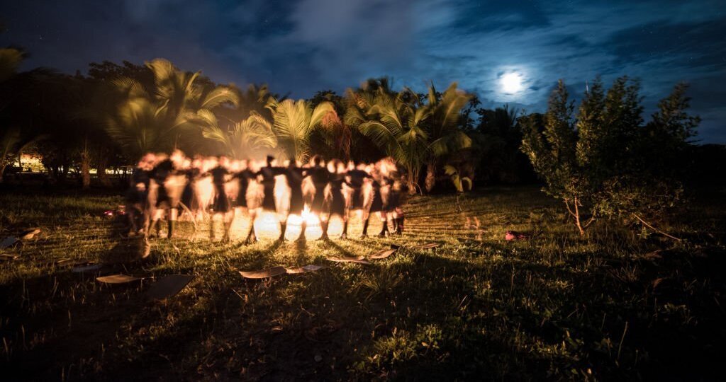 A beautiful shot of people dancing around a campfire