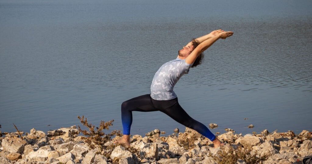 Young man practicing yoga by the lake