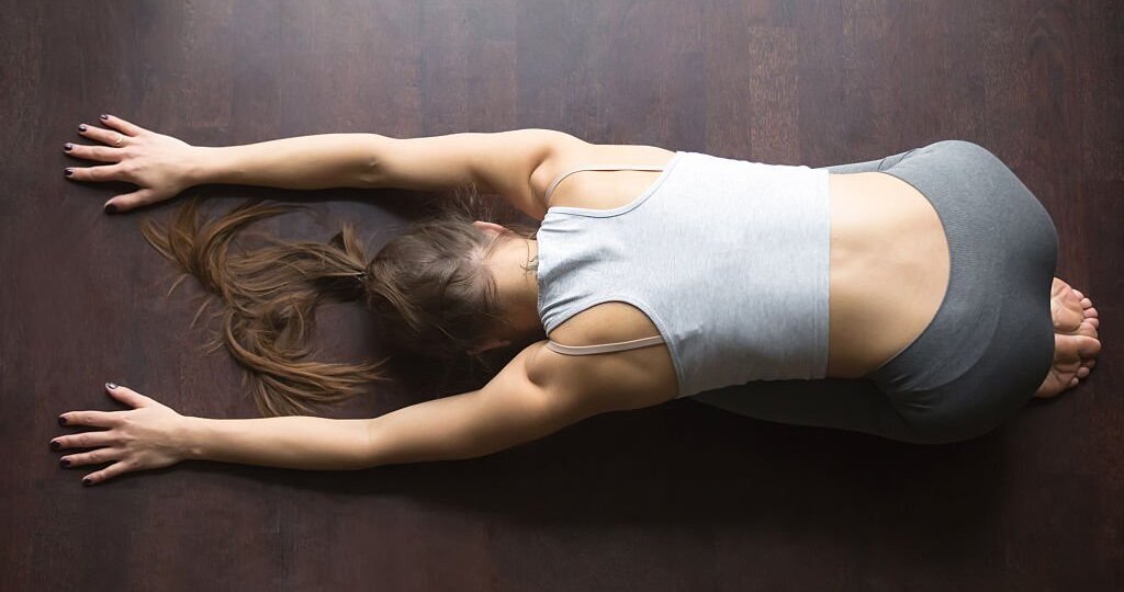 Girl doing yoga exercise for spine on wooden floor