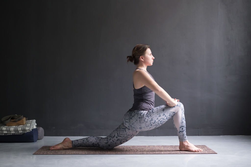 Woman doing Hatha yoga asana Anjaneyasana 