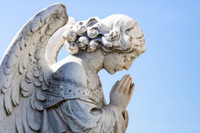 Old statue of praying angle in cemetery 