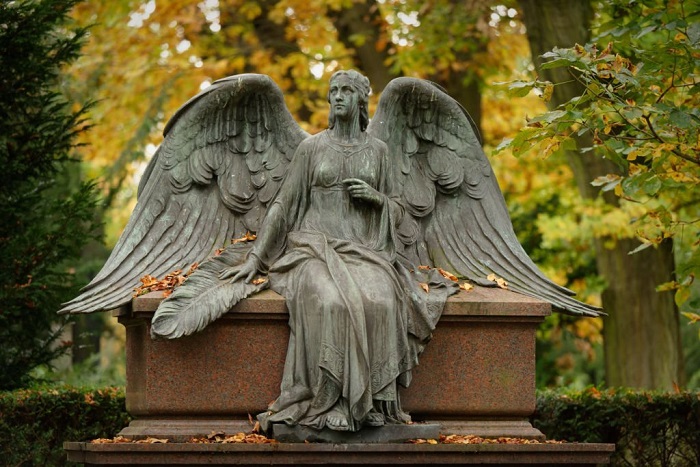 Beautiful angel with spread wings on a cemetery in autumn mood