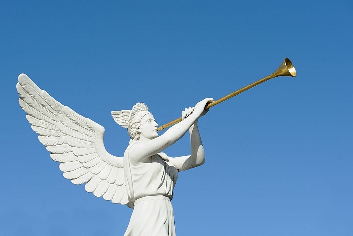 Statue of an angel trumpeter against a clear, blue sky