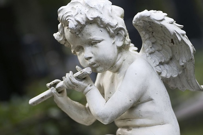 Statue of a little angel on cementery.