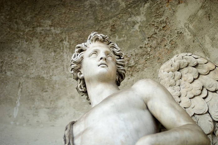 White marble angel looks out from a gritty stone alcove