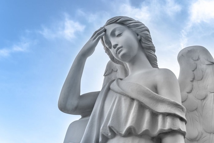 Ancient statue of an angel of peace with the hand with the hand on the forehead