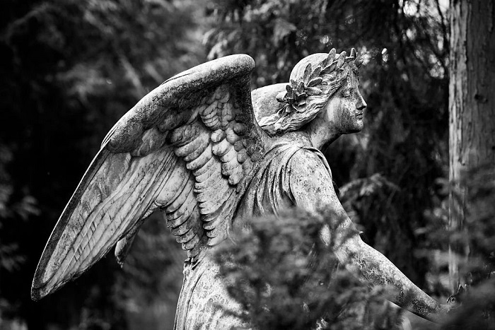 Old and weathered contemplating angel on an abandoned grave
