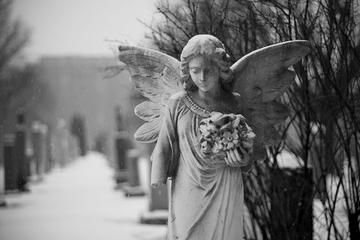 Angel statue with a broken arm in a snowy winter day. Côte-des-Neiges cemetery / Montréal