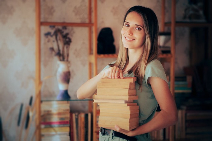 Cheerful novel collector holding many textbooks