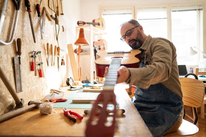 Craftsman at workbench repairing the classical guitar