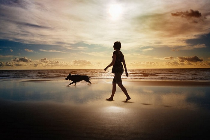 Grace and her dog walking on the beach 