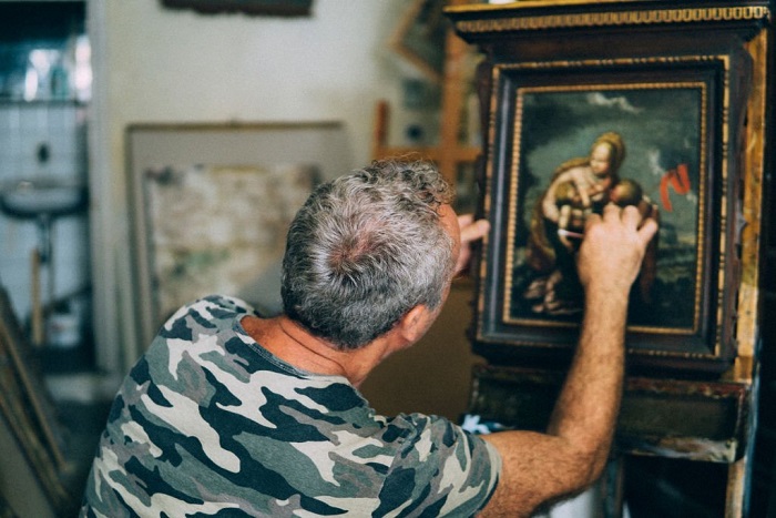 Grady a restorer repairing an ancient canvas in his workshop