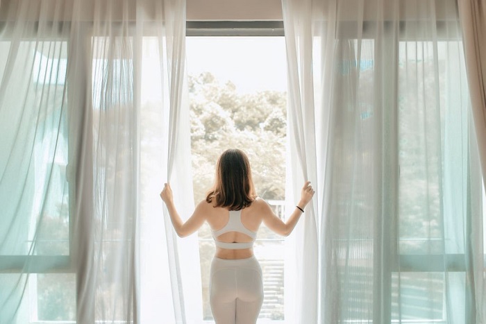 Josephine opening curtain and walking out to the balcony in the morning getting ready to practice yoga