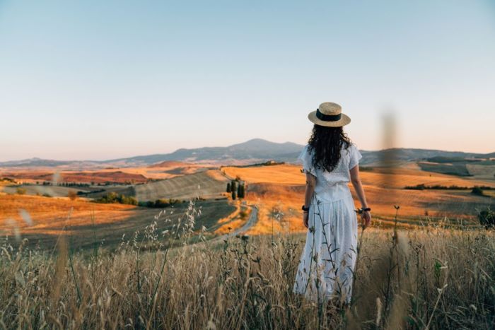 Madeline admiring sunset in a wheat field in Tuscany