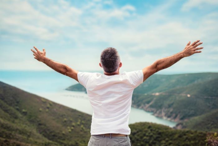 Maverick with arms outstretched on mountaintop