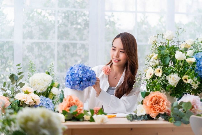 Natalie smiles while arranging flowers in floral shop