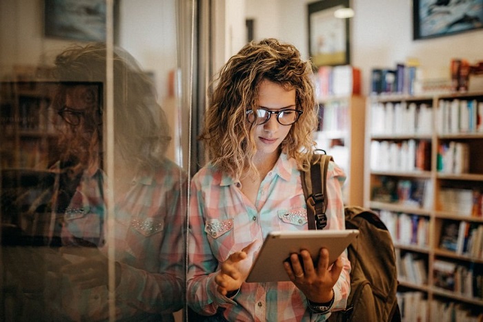 Sabrina using digital tablet at library to find right publication