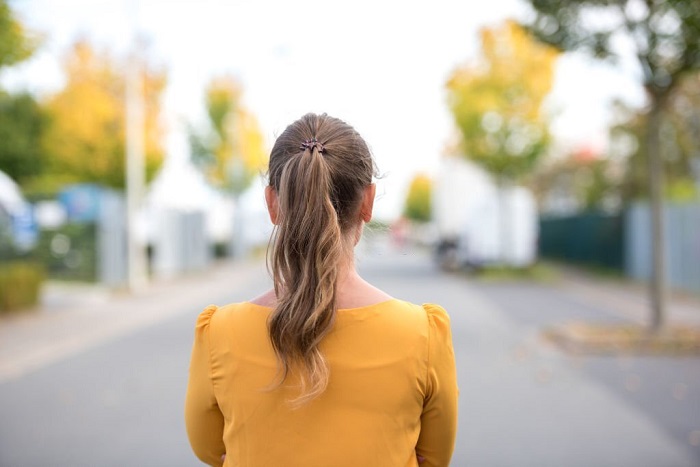 Rear view of Skylar wearing yellow dress standing on the street in autumn weather