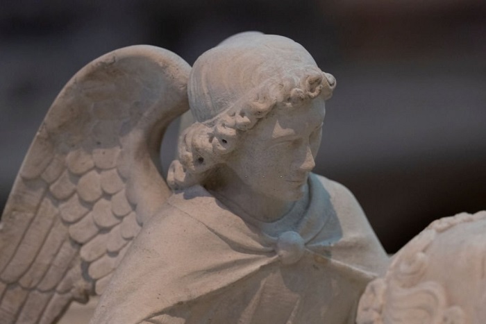 Close up detail of angel in a cathedral carved in marble showing tip of wing
