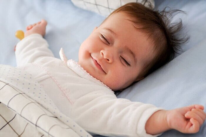 Smiling baby girl lying on a bed