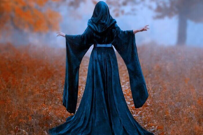 Young priestess holds a secret rite of sacrifice, is alone in the autumn forest on a large glade
