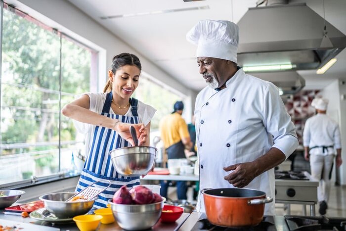 Source: Istockphoto. Student cooking and teacher helping in a cooking class