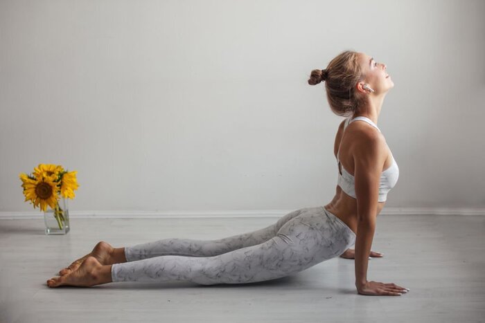 Source: Istockphoto. Yoga woman doing upward-facing dog pose against a white wall