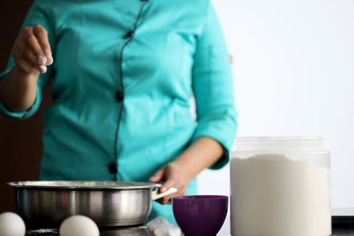 Source: Istockphoto. A chef's hand preparing whipping flour for cake with kitchen utensils