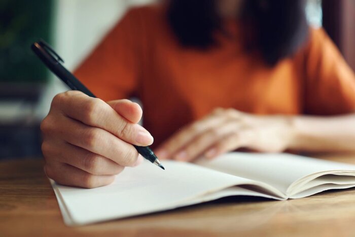 Source: Istockphoto. Close up woman hand writing on notebook 