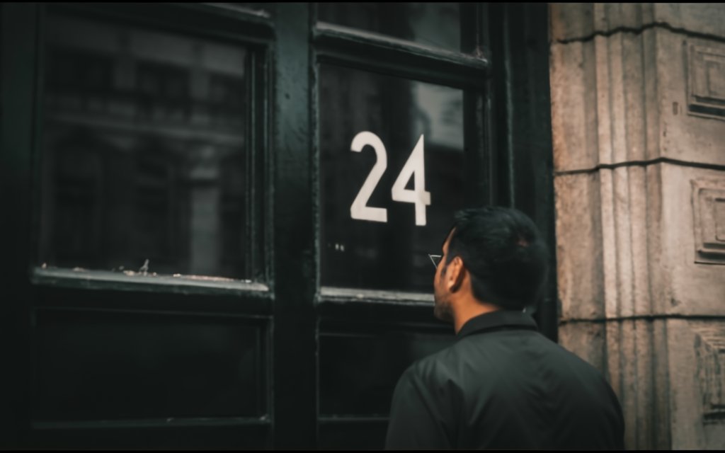 A man looking at a sign of 24 on a window